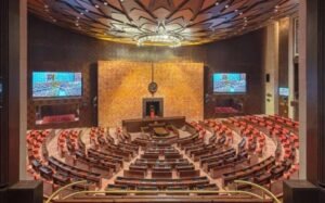 Interior view of the Rajya Sabha chamber inside the Parliament House, New Delhi, showing semicircular seating arrangement, the Chairperson’s podium, and members’ desks during a session.